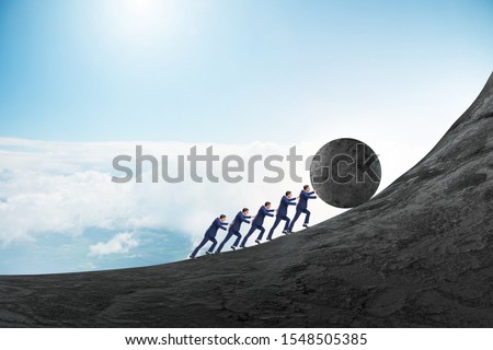 Team of people pushing stone uphill Royalty-Free Stock Photo #1548505385