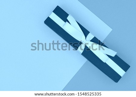 Gift box on a paper background close up. Flat lay top view copy space. Blue color toned