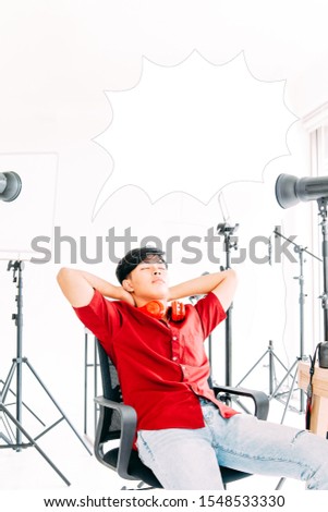Young Photographer sitting on his chair with equipment in studio and imagine his future successful.