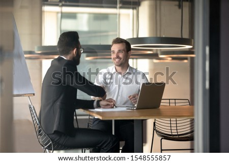 Happy successful multiracial businessmen handshake greeting or get acquainted at office meeting, smiling diverse male colleagues or partners shake hands closing deal after successful negotiation