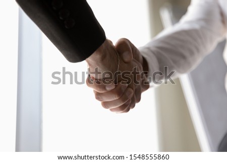 Crop close up of businessman shake hands greeting or getting acquainted at meeting or briefing, businesspeople or partners handshake closing deal after successful negotiations, cooperation concept