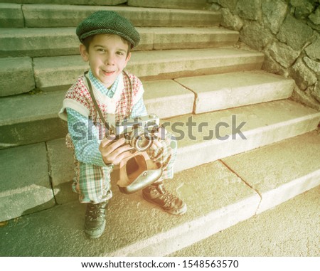 Child with vintage camera. Exterior stairs. Vintage kid photographer. 