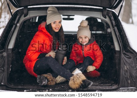 Mother with daughter sitting in car in winter