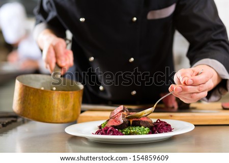 Chef in hotel or restaurant kitchen cooking, only hands, he is working on the sauce for the food as saucier, a Risotto Royalty-Free Stock Photo #154859609
