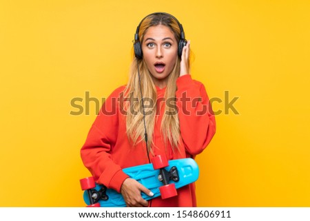 Young skater woman doing surprise gesture over isolated yellow background