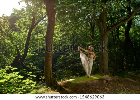 Asian woman doing balance on one leg Asana yoga pose Beautiful portrait of yoga Outdoors lifestyle portrait. Summer relaxation Nature background Healthy lifestyle Outdoor activity Yoga in modern style