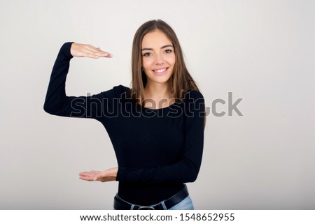 Blonde European woman over isolated background gesturing with hands showing big and large size sign, measure symbol. Smiling looking at the camera. Measuring concept.