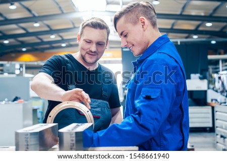 Skillful master discussing a workpiece with his apprentice or trainee Royalty-Free Stock Photo #1548661940
