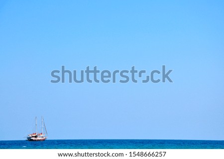 Tourist sailboat on the horizon with blue sky in the background during vacations in Cyprus