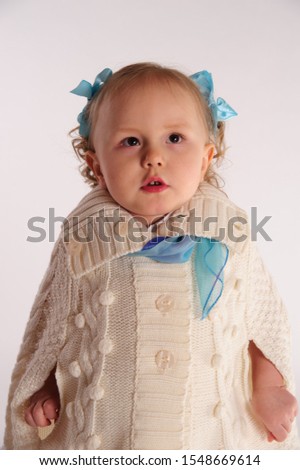 little girl in a woolen knitted wrap - poncho on a white background in the studio