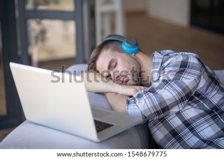 Freelancer falling asleep. Bearded freelancer falling asleep near his laptop after working for too long Royalty-Free Stock Photo #1548679775