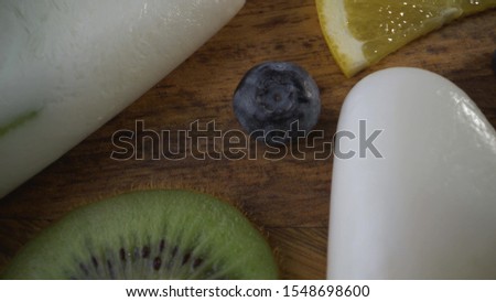 Summer food: cooking home-made fruit ice with with fresh fruits and berries. Slices orange and kiwi, blueberries on a wooden table with natural yogurt ice cream