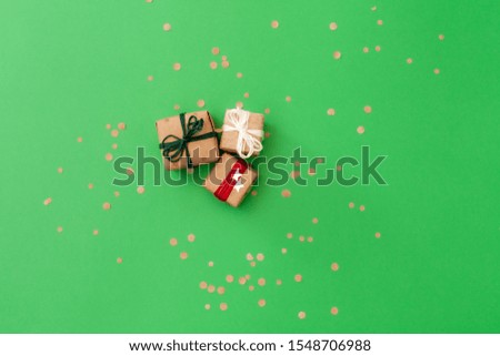 Three handcraft gifts on green background with confetti top view, place for your text
