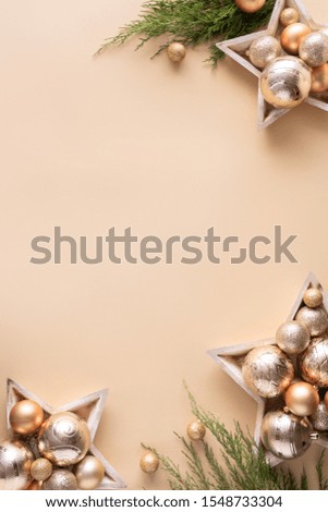 Happy new year background, merry christmas concept, gold decorations baubles in wooden stars with fir tree branches on light beige table pastel background, flat lay copy space top vertical view above