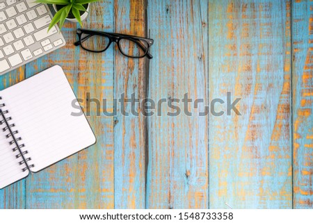 Minimalist flat lay composition of book, plant and glasses on the wooden table top view