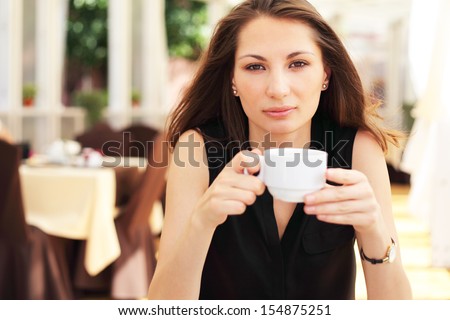 Image of young woman drinks coffee in cafe