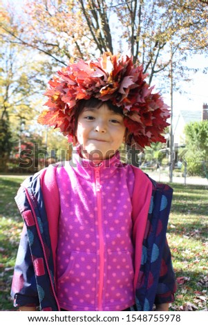 Cute little girl in autumn leaves wreath