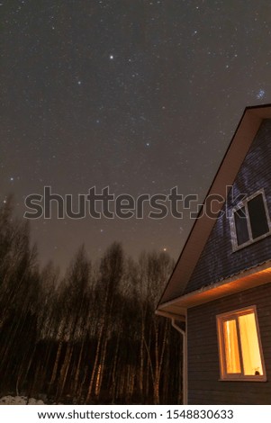 A house in the forest under a winter night sky