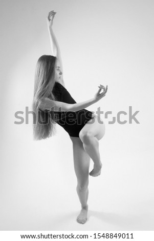 beautiful young girl in black bodysuit dancing in a studio on a white background