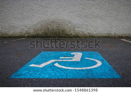 Disabled parking sign painted on the ground of a car park. Parking lot space for persons with disability.