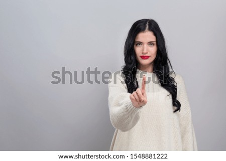 Young woman pointing at something on a gray background