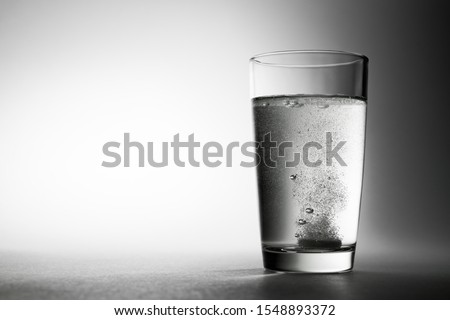 Effervescent aspirin tablet dropping to glass of water