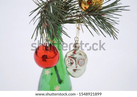 Close-up of a pine branch decoration with  vintage toys in green bottle vase on a white snow background. New year and Christmas concept. Сopy space. Place for text.