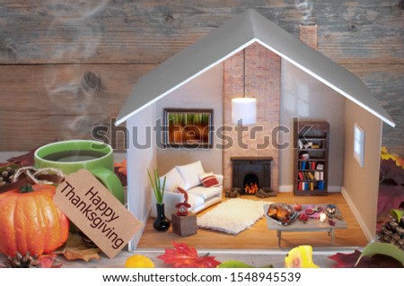Happy thanksgiving label attached to miniature house living room and fireplace, with seasonal food laid out on a table