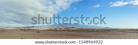View on mountains from a long sandy beach with a beautiful cloudy blue sky
