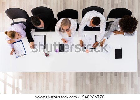 Panel Of Corporate Personnel Officers Sitting At A Table Royalty-Free Stock Photo #1548966770