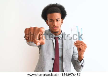 Young african american businessman holding boarding pass over isolated white background pointing with finger to the camera and to you, hand sign, positive and confident gesture from the front