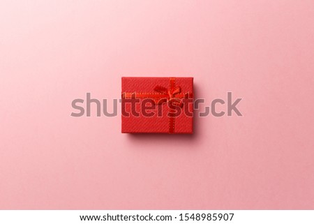 Red gift box with red ribbon on pink background. Top view. Flat lay. Copy space. Colorful background. Minimal christmas new year creative concept. Trendy pastel color