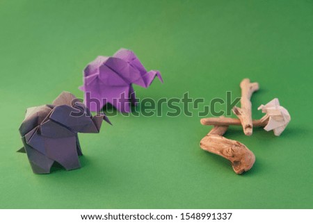 origami elephants made of colour paper on green background. paper and forest conservation concept. family and childhood. mockup, copy space