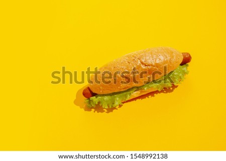 Hot dog on a yellow background with ketchup and mustard