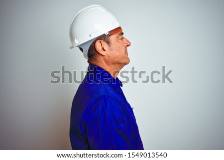 Handsome middle age worker man wearing uniform and helmet over isolated white background looking to side, relax profile pose with natural face with confident smile.