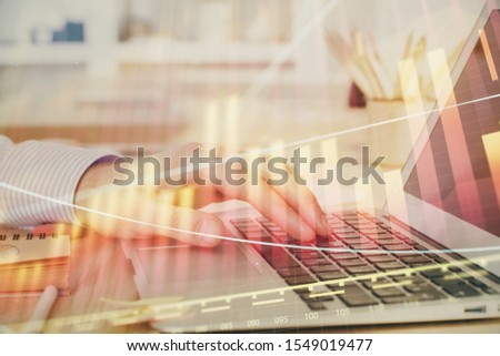 Double exposure of man's hands writing notes with laptop of stock market with forex graph background. Top View. Concept of research and trading.