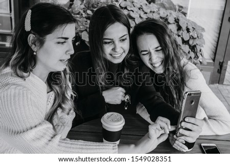 Black and white photo of girlfriends with a smartphone, girlfriends take selfies.