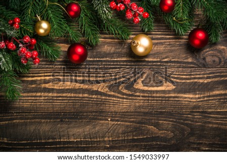 Christmas flat lay background with fir tree branch and red decorations on dark wooden table. Free space for design.