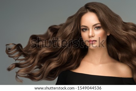 Beauty brunette girl with long  and   shiny wavy black hair .  Beautiful   woman model with curly hairstyle .