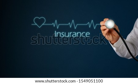 Glowing heart shape and cardiogram on virtual interface with male hand holding stethoscope next to it and Insurance sign under the frequency graph.