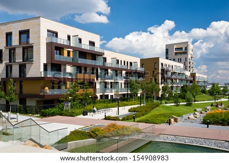 View of public park with newly built modern block of flats under blue sky with few clouds Royalty-Free Stock Photo #154908983