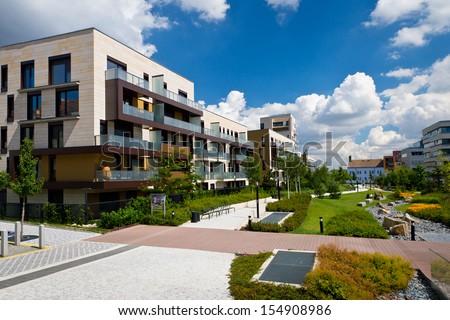 View of public park with newly built modern block of flats under blue sky with few clouds Royalty-Free Stock Photo #154908986