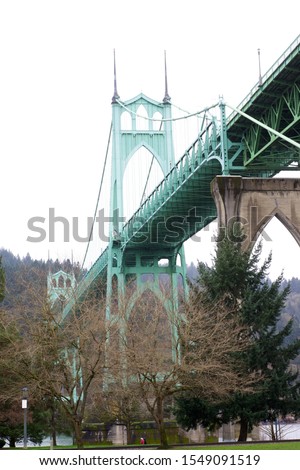 A vertical low angle shot of the famous St. Johns Bridge surrounded by a forest in Portland, Oregon, United States