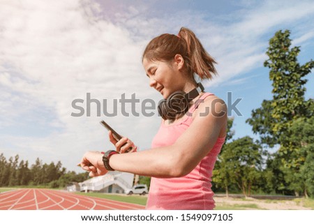 Sporty asian woman runner in fashionable sportswear, Concepts of running and exercise for health, Watching a smartphone and a smartwatch.