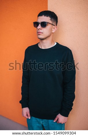 City portrait of handsome hipster guy with beard wearing black blank hoody or sweatshirt with space for your logo or design. Mockup for print