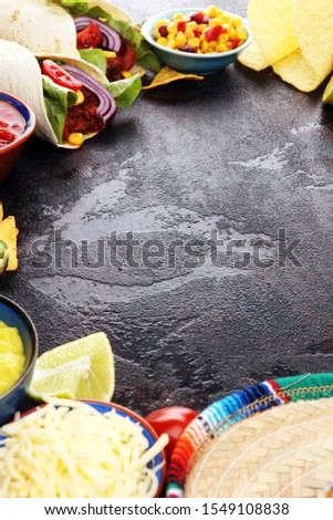 Mexican food, including tacos, guacamole, nachos and pepper on table