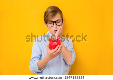 Business man. Surprised teenage boy holding a red piggy Bank. Business concept. Saving money concept. Bank advertising. Piggybank. Financial bankrupt