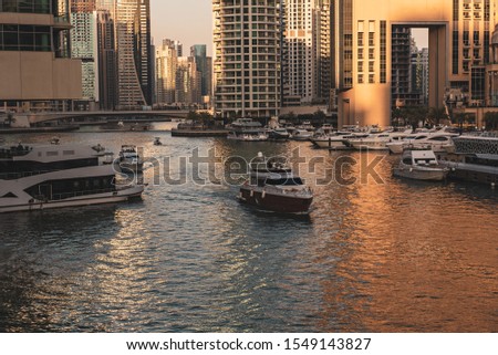 Dubai Marina before sunset with skyscrapers, boats and reflections in the water, United Arab Emirates