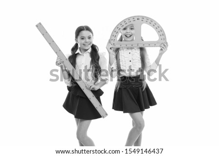 Geometry lesson is much fun. Little girls holding protractor and ruler for lesson. Small children with measuring instruments at school lesson. Cute schoolgirls preparing for geometry lesson.