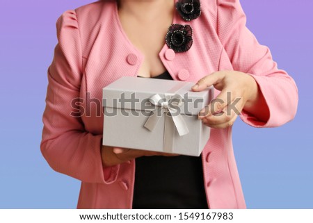 woman holding a gift in a light gray box with a satin ribbon and a bow, concept of Valentine's Day, Christmas presents, mother's day, new year, close-up, copy space